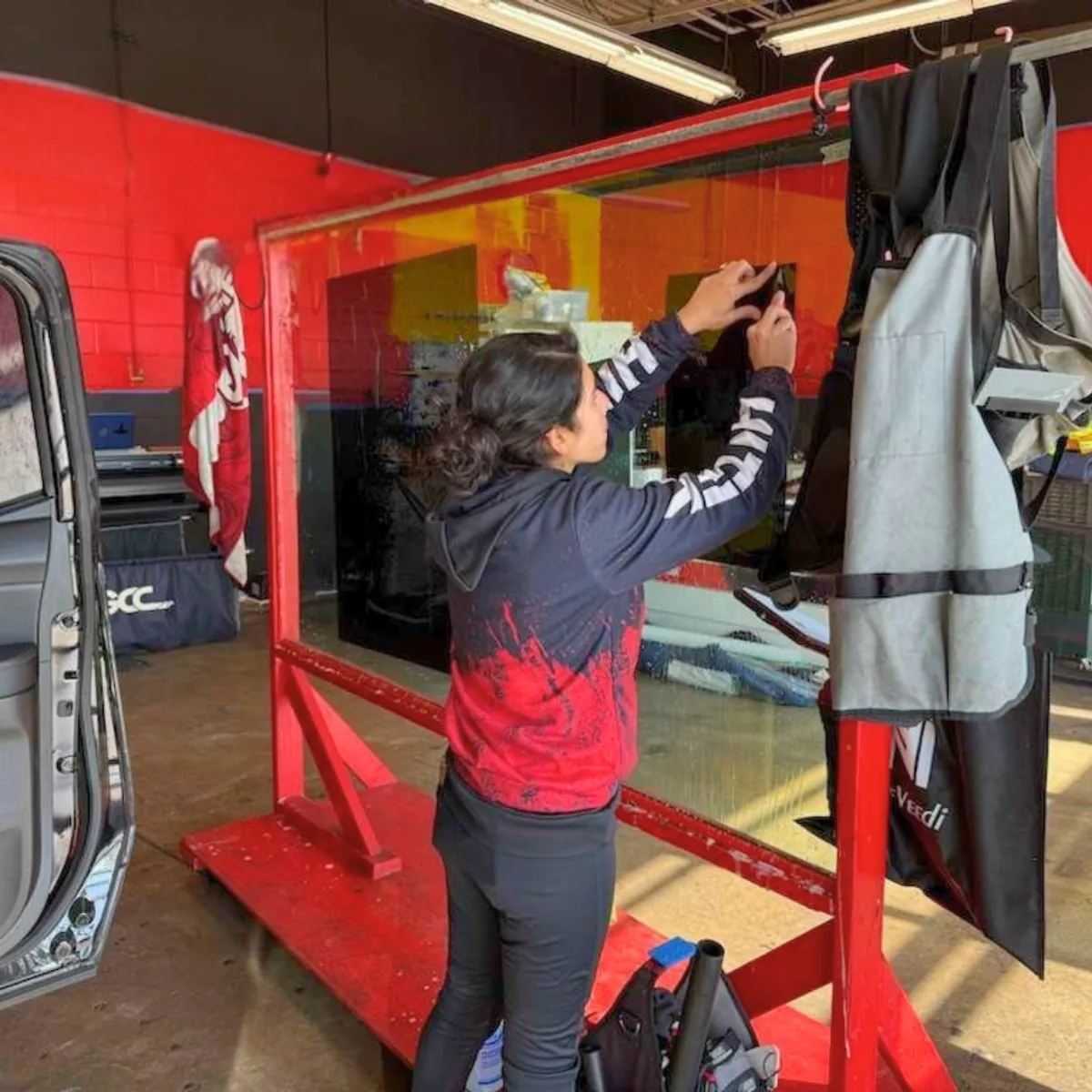 AGC crew hand-cutting window tint in the shop